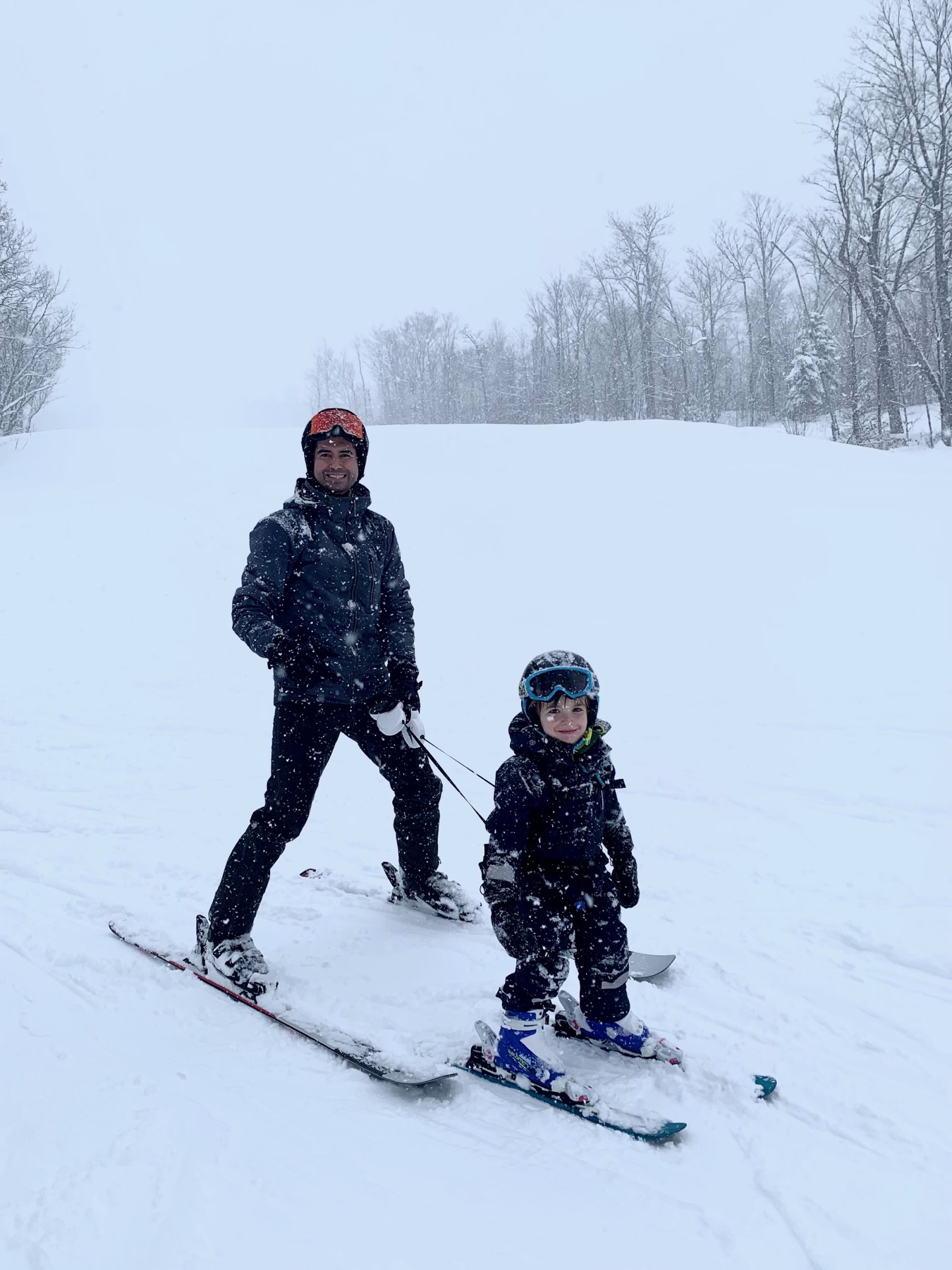 A parent and young child skiing together during a Sugarloaf snowstorm